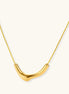Minimalist gold-plated curved pendant necklace on delicate chain against cream background, showing adjustable length