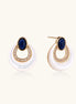 Gold drop earrings with oval lapis lazuli, crystal-paved frame, and iridescent mother-of-pearl teardrop on cream background