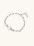 Rhodium-plated silver chain bracelet with single white freshwater pearl and heart charm clasp on cream background