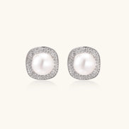 Rhodium-plated sterling silver stud earrings with round freshwater pearls surrounded by geometric crystal halos on cream background.