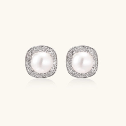 Rhodium-plated sterling silver stud earrings with round freshwater pearls surrounded by geometric crystal halos on cream background.