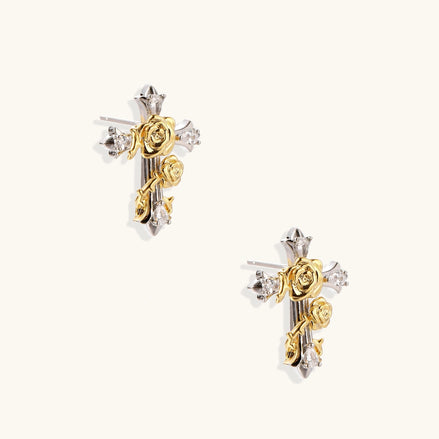 Gold-plated cross earrings with dimensional roses and crystal details on cream background, 18k gold over brass construction.