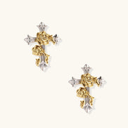 Gold-plated cross earrings with dimensional roses and crystal details on cream background, 18k gold over brass construction.