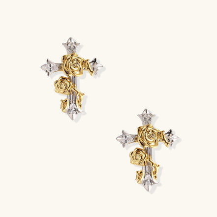 Gold-plated cross earrings with dimensional roses and crystal details on cream background, 18k gold over brass construction.