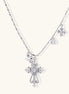 Ornate white gold-plated cross pendant with zirconia stones and pearl accents on adjustable silver chain against cream background