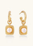 Pair of gold vermeil hoop earrings with textured square frames holding freshwater pearls on cream background