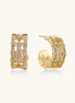 Gold-plated geometric hoop earrings with basket-weave lattice design and pavé crystal accents on cream background