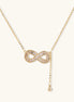 Gold infinity pendant with baguette crystals on adjustable chain against cream background.