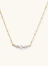 Delicate 14K gold-plated necklace with five graduated zirconia stones arranged in a curved arc on fine chain