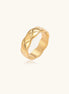 Close-up of an 18K gold-plated twisted band ring with dimensional braided pattern on cream background.