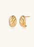 Chunky gold twisted rope huggie hoops with diagonal grooves and high-polish finish on cream background