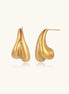 Organic sculptural gold stud earrings with fluid matte finish on cream background