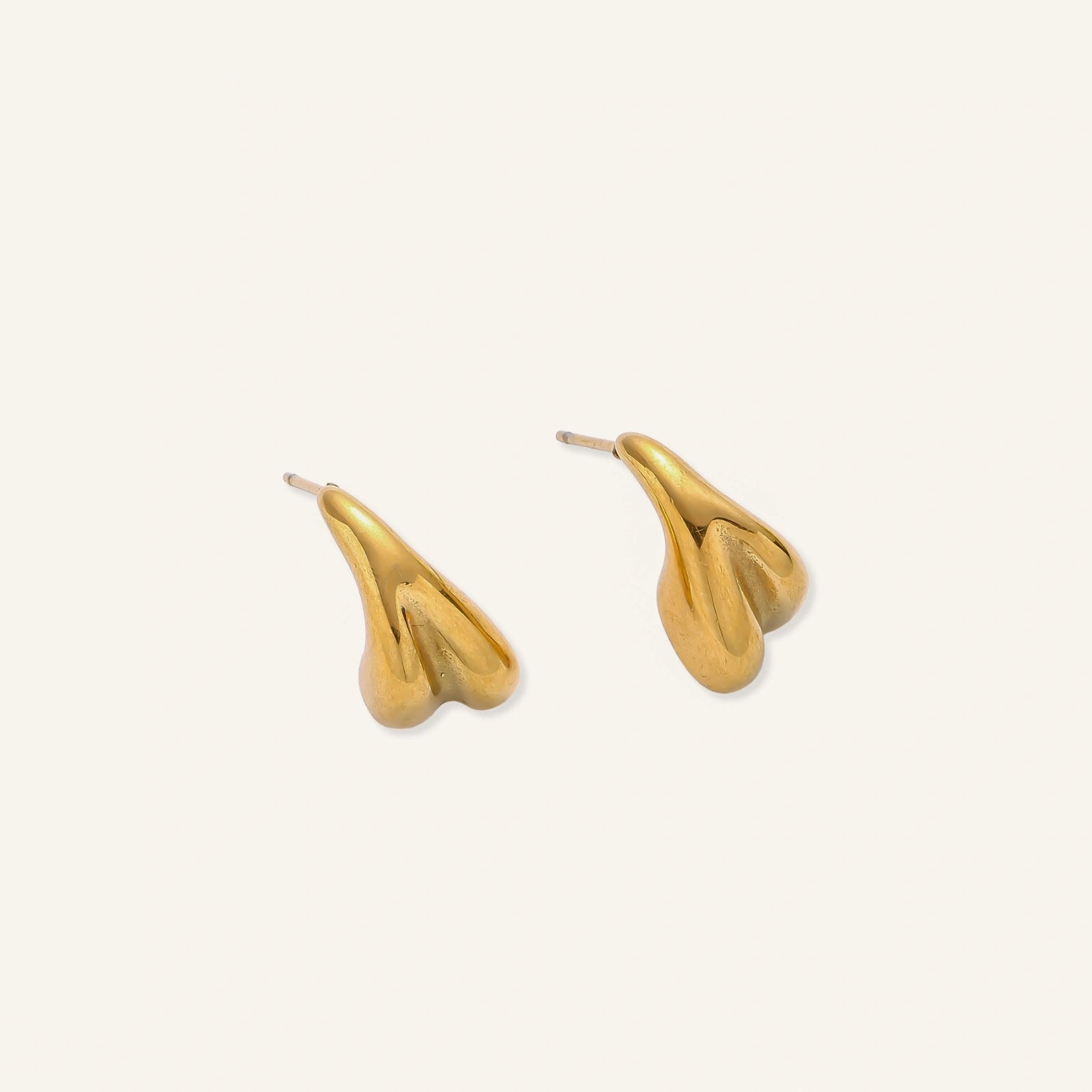 Organic sculptural gold stud earrings with fluid matte finish on cream background