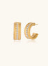 Textured gold huggie hoop earrings with raised ribbed rows creating dimensional sculptural design on cream background