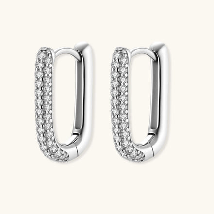Close-up of platinum-plated sterling silver huggie hoops with pavé crystal setting on white background.