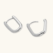 Close-up of platinum-plated sterling silver huggie hoops with pavé crystal setting on white background.